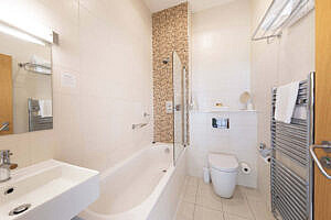 Ensuite bathroom showing bath, basin and heated towel rail
